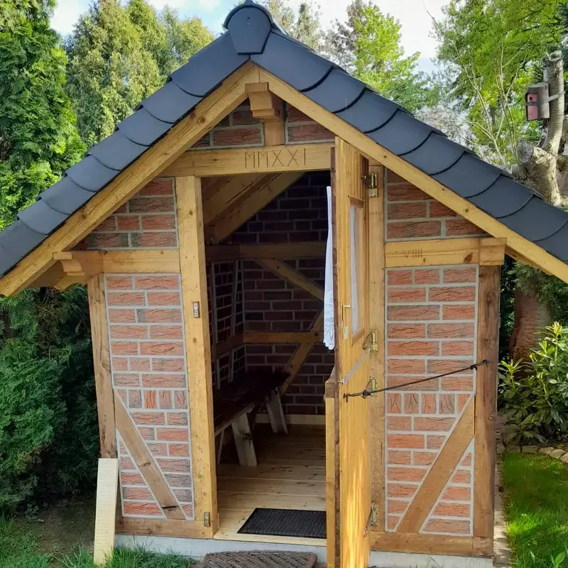 Individuelle Holzbauprojekte – handgefertigtes Gartenhaus aus Holz mit Ziegelausfachung und Schieferdach